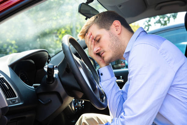 man leaning head on steering wheel inside car